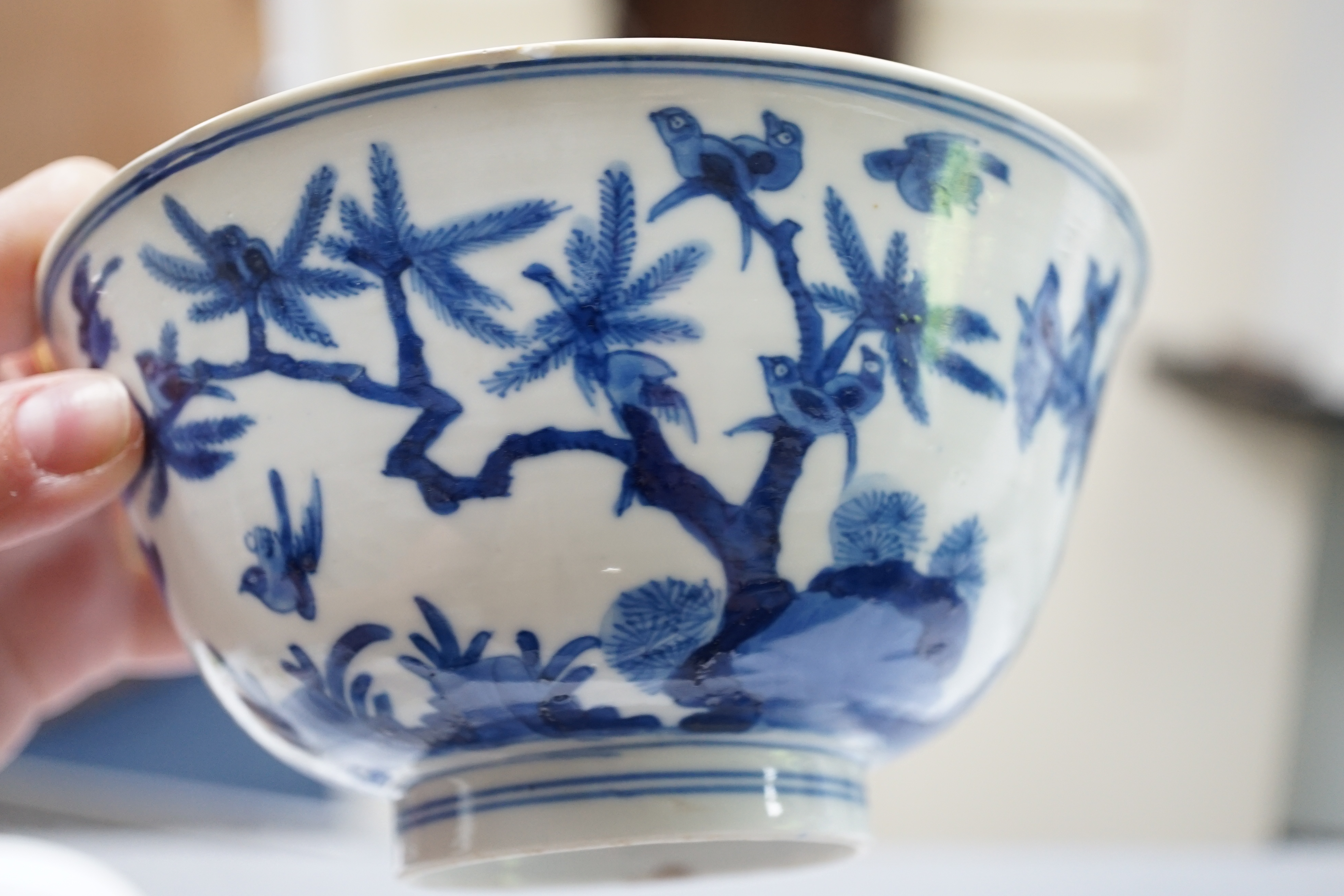 A near pair of Chinese blue and white ‘birds’ bowls, Kangxi period, one bowl restored